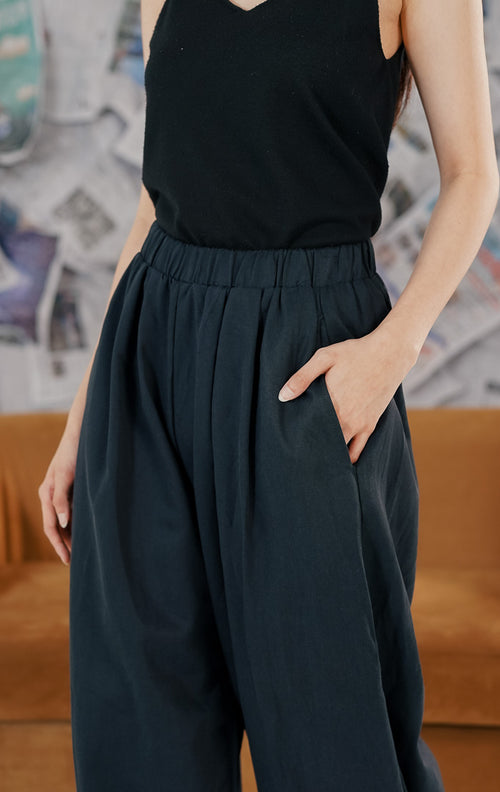 Model wanita mengenakan Jaehee Pants Blue, celana panjang model balon warna biru dongker berbahan katun dengan saku samping, dipadukan dengan sepatu flat polkadot.