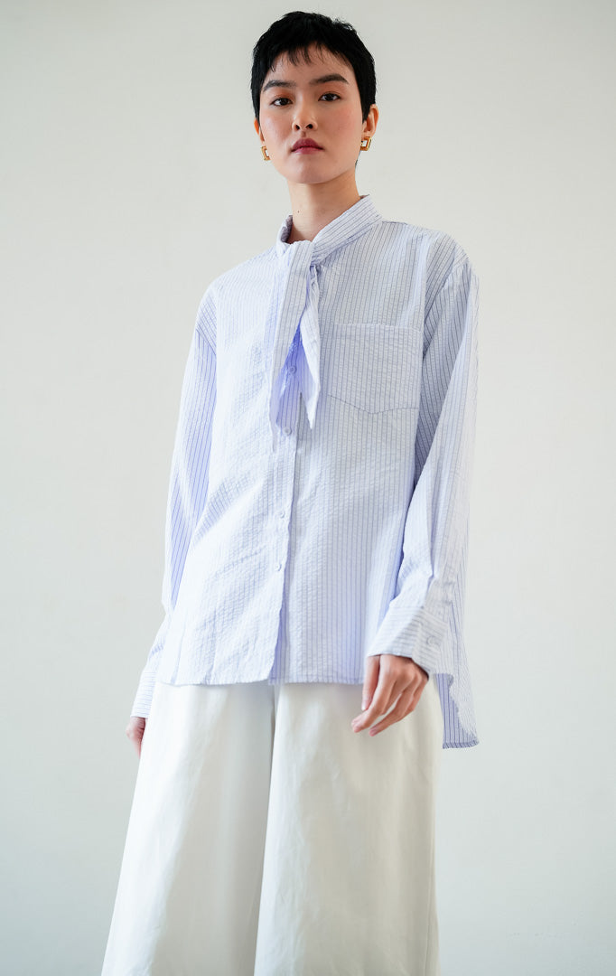Kemeja wanita lengan panjang motif garis-garis warna ungu (purple striped) Jaylee Top berbahan tekstur ringan (lightweight textured fabric) dengan kerah dasi (tie-neck collar), bukaan kancing depan, dan kelim melengkung (curved hem