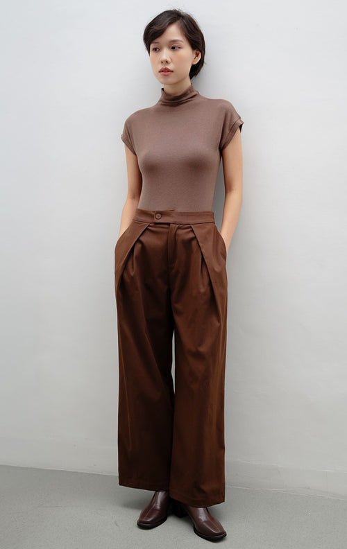 Celana panjang wanita warna cokelat tua (dark brown) Jelson Pants dengan detail lipit halus (partial pleats) di bagian depan untuk tampilan rapi dan efek kaki jenjang.