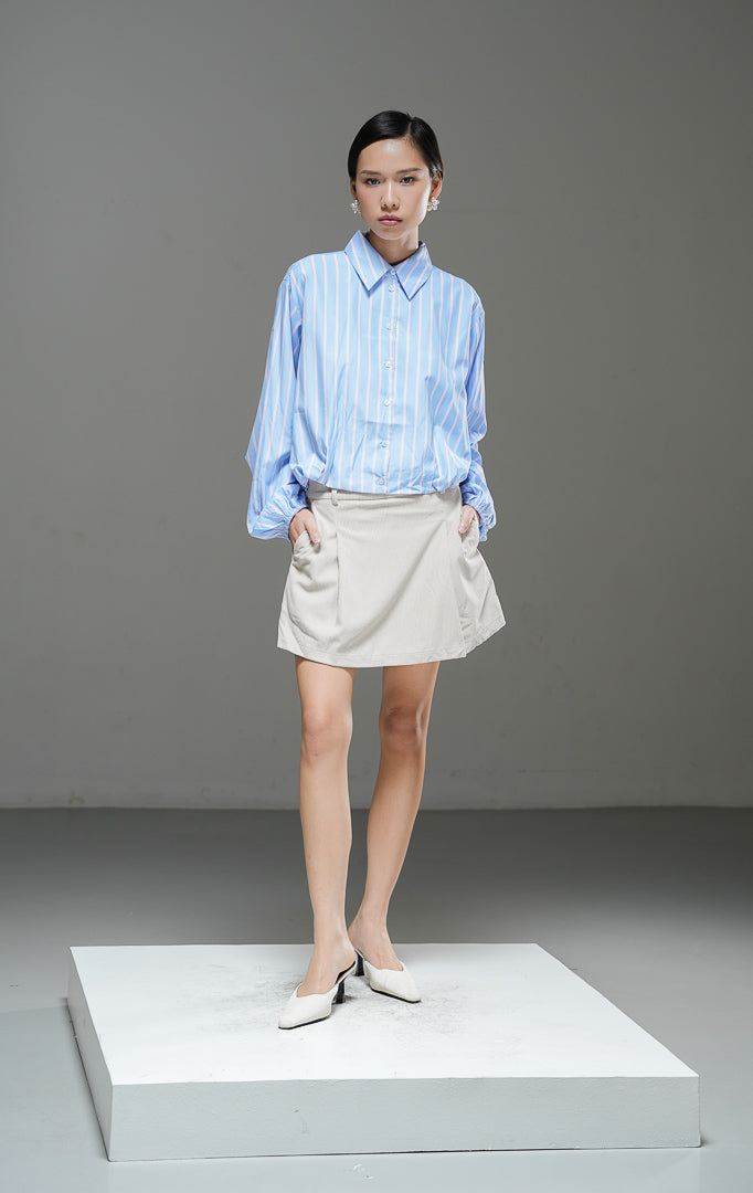 Kemeja crop wanita Jemima Top warna biru motif garis salur (striped) berbahan katun poplin dengan kerah kemeja dan detail karet bagian bawah. 
