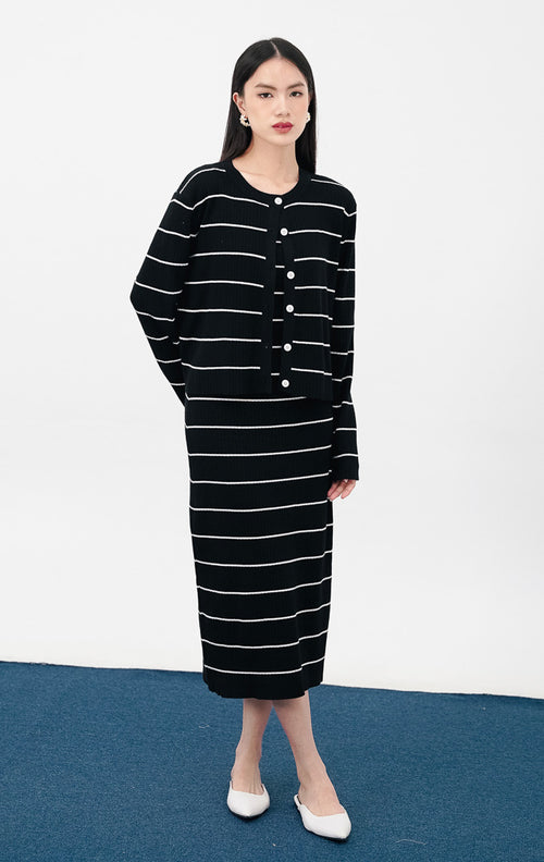 Model mengenakan Jennet Dress Set warna black, setelan yang terdiri dari gaun rajut tanpa lengan motif garis horizontal putih dan cardigan outer senada.