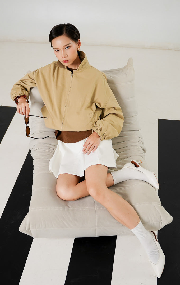 Jaket wanita Jeslyn Outer Khaki dengan detail kerah, bukaan resleting (zipper) depan, saku samping, dan karet elastis pada pinggang serta pergelangan tangan. 