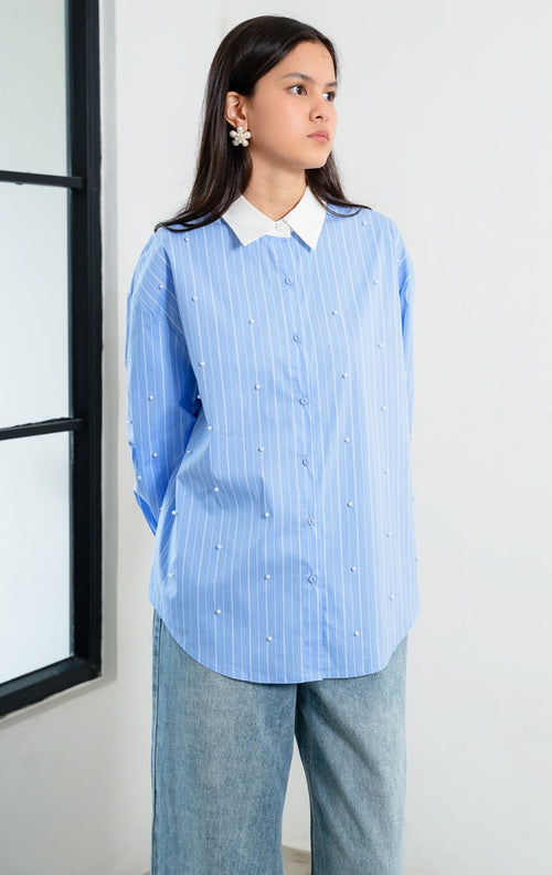 Kemeja wanita lengan panjang motif garis-garis biru (blue striped) Jeyra Top dengan aksen hiasan mutiara (pearl embellishments), kerah dan manset kontras warna putih (contrasting collar and cuffs), serta kelim melengkung (curved hem). 

