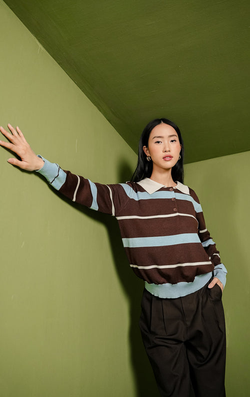 Sweater rajut wanita Julia Sweater lengan panjang dengan kerah polo berwarna krem, detail tiga kancing depan, dan motif garis horizontal perpaduan blok warna cokelat, biru muda, serta garis tipis krem.