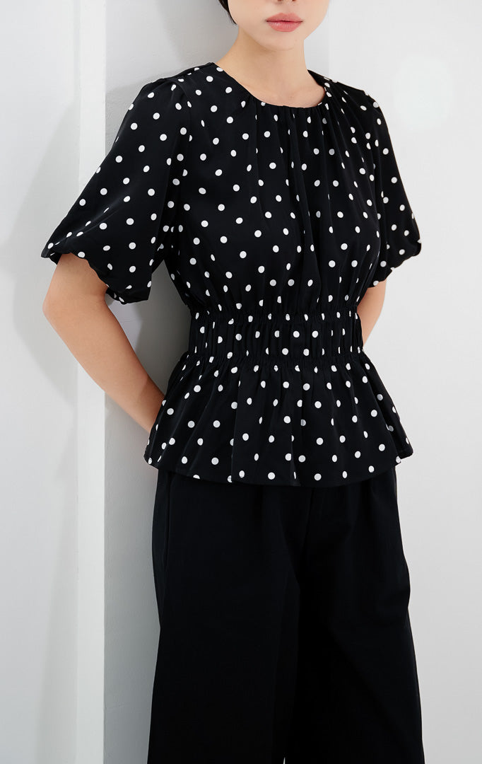 Atasan wanita warna hitam Julietta Top bermotif polkadot dengan detail lengan balon (puff sleeves) dan badan berkerut (smocked bodice).
