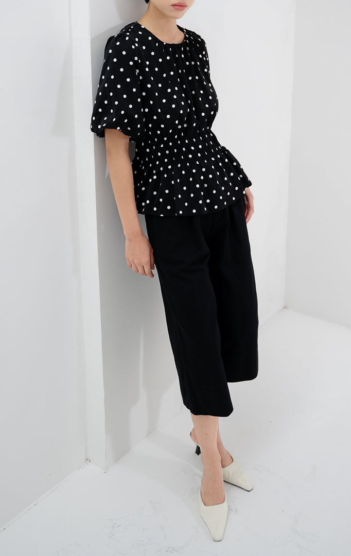 Atasan wanita warna hitam Julietta Top bermotif polkadot dengan detail lengan balon (puff sleeves) dan badan berkerut (smocked bodice).