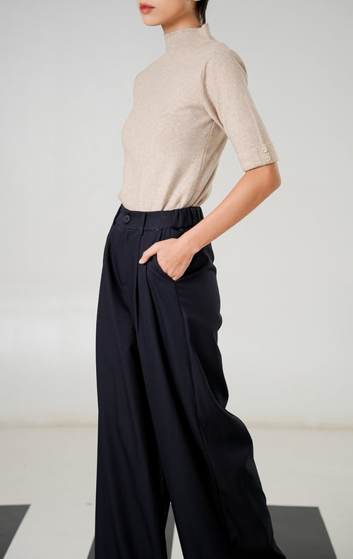 Celana panjang wide leg Kaelith Navy dengan detail lipit (pleats) depan, kancing senada, dan ban pinggang elastis belakang dari This Is April. 