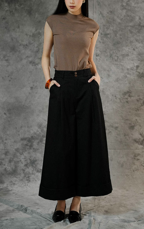 Celana panjang kulot wanita Kahi warna hitam dengan cutting wide leg, detail double kancing depan, saku samping, dan aksen lipatan besar di ujung bawah.