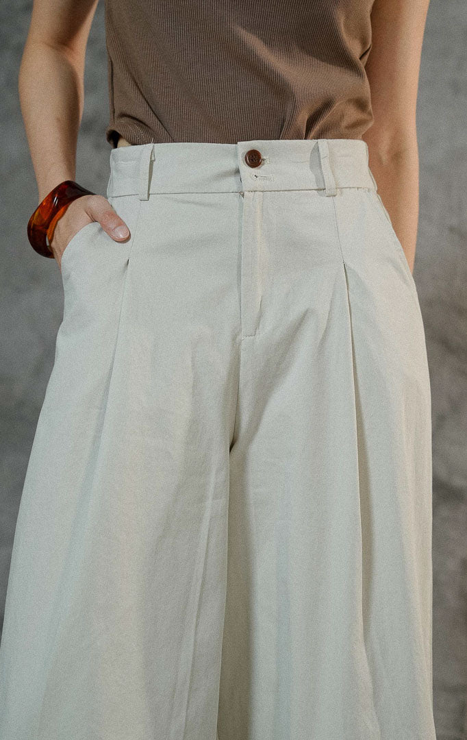 Celana kulot wanita Kahi warna ivory berbahan katun dengan siluet wide leg yang flowy, dilengkapi karet pinggang belakang dan resleting depan.
