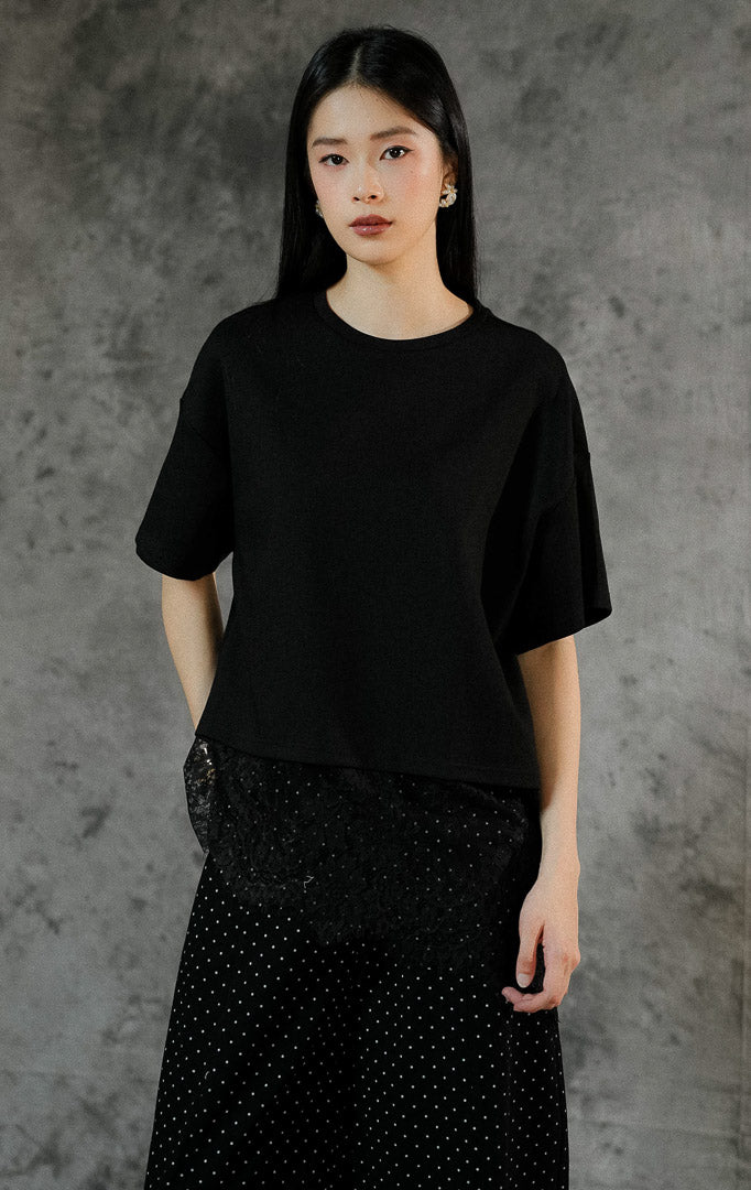 Kemeja oversized lengan panjang wanita Kaori warna hitam berbahan katun dengan detail aksen renda lace manis di sepanjang keliman hem bawah. 