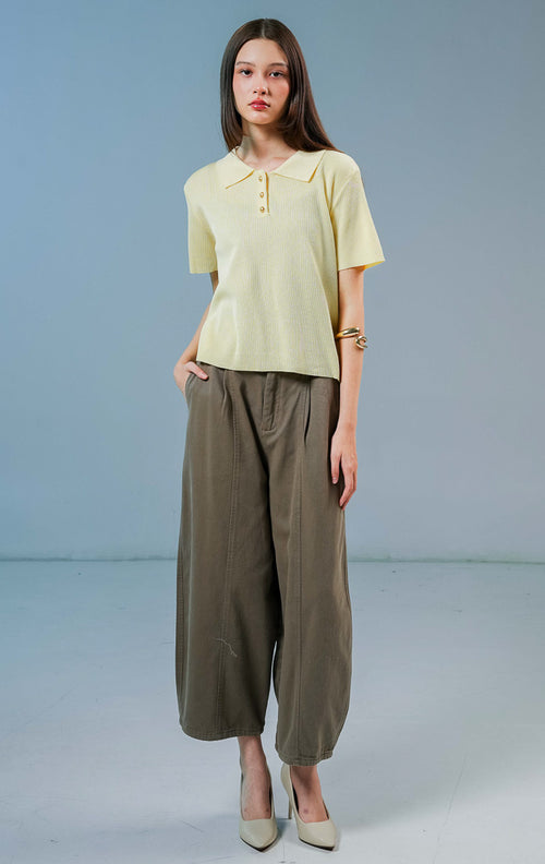 Model wanita mengenakan Griffin Collared Short Sleeve Top warna kuning muda, baju kaos rajut wanita lengan pendek dengan kerah polo terstruktur dan kancing emas depan. 
