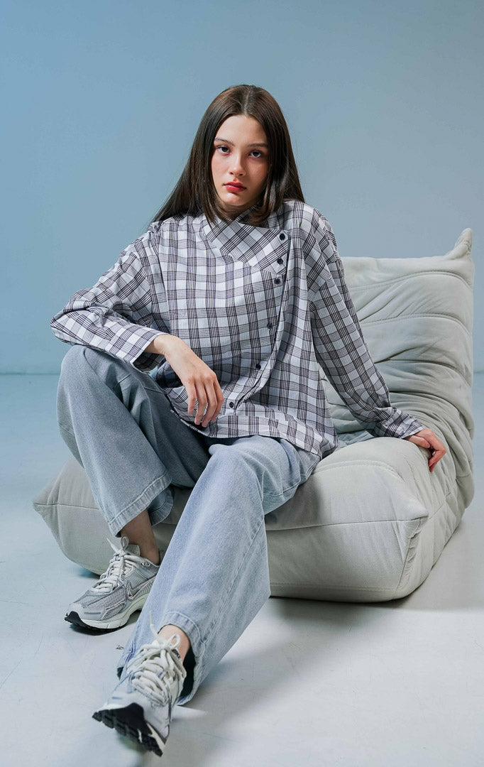 Model wanita mengenakan Joseph Plaid Top warna blue, kemeja katun lengan panjang motif kotak-kotak dengan detail kerah tinggi dan kancing asimetris depan. 
