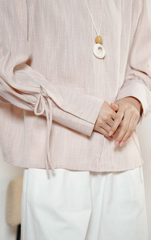 Detail dekat lengan Madden Ribbon-Detail Long-Sleeve Shirt warna pink, kemeja blouse wanita warna merah muda pastel dengan manset panjang berdetail tali pita simpul yang feminin. 