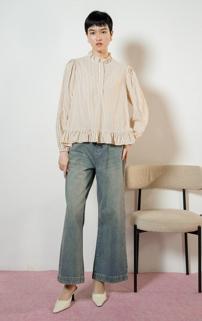 Model wanita mengenakan Alessia Frill-Hem Striped Top warna butter yellow, blouse kemeja salur wanita motif garis kuning dengan detail kerah ruffle dan ujung kelim berkerut yang feminin. 