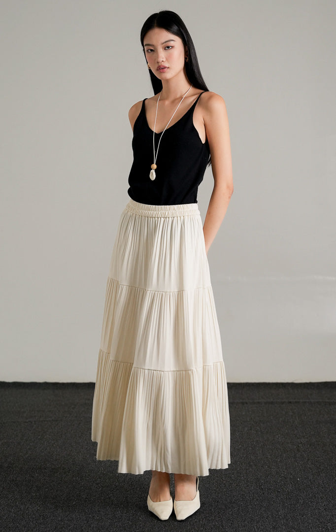 Kenny Skirt Ivory, rok panjang lipit bertingkat warna krem dengan pinggang karet, dipadukan dengan tank top hitam dan kalung.