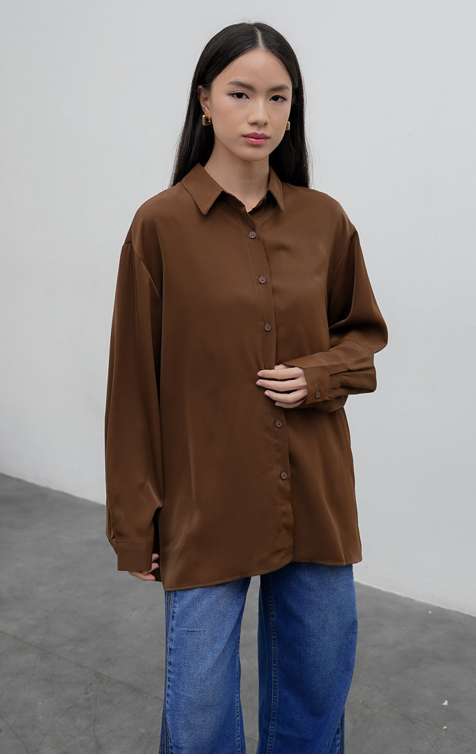 Kemeja polos wanita lengan panjang warna cokelat tua (dark brown) Kierana Top berbahan smooth polyester halus dengan kerah kemeja klasik dan bukaan kancing depan.