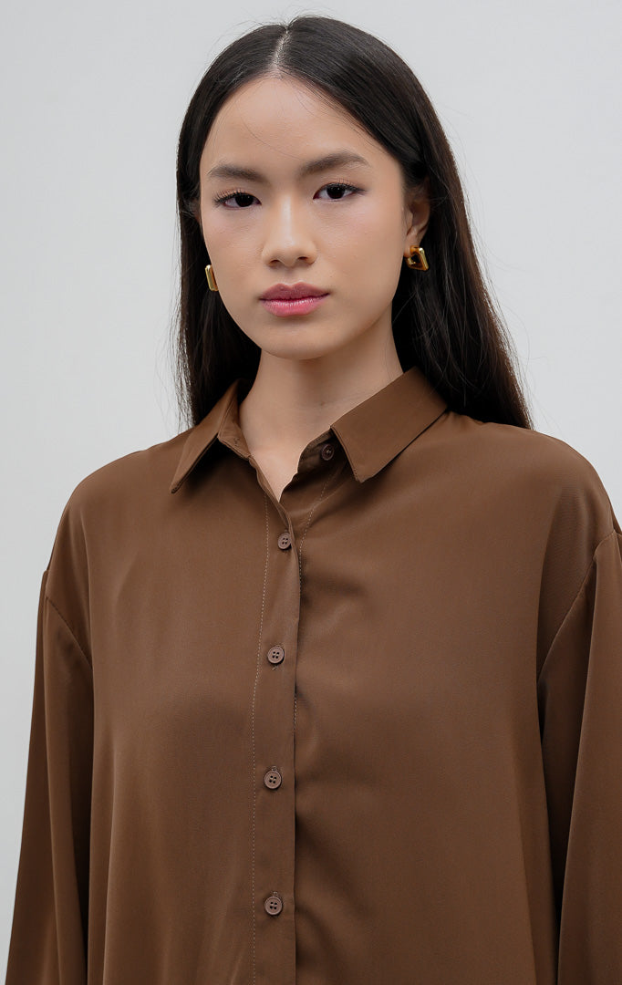 Kemeja polos wanita lengan panjang warna cokelat tua (dark brown) Kierana Top berbahan smooth polyester halus dengan kerah kemeja klasik dan bukaan kancing depan.