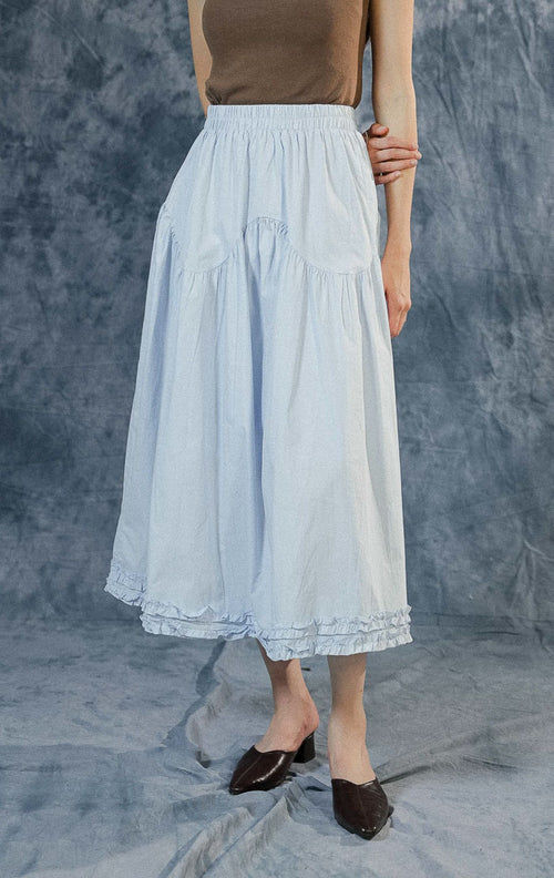 Rok panjang (maxi skirt) wanita Lacey warna biru berbahan katun dengan detail tingkat (tiered), jahitan bergelombang di tengah, aksen ruffle bawah, dan pinggang karet.