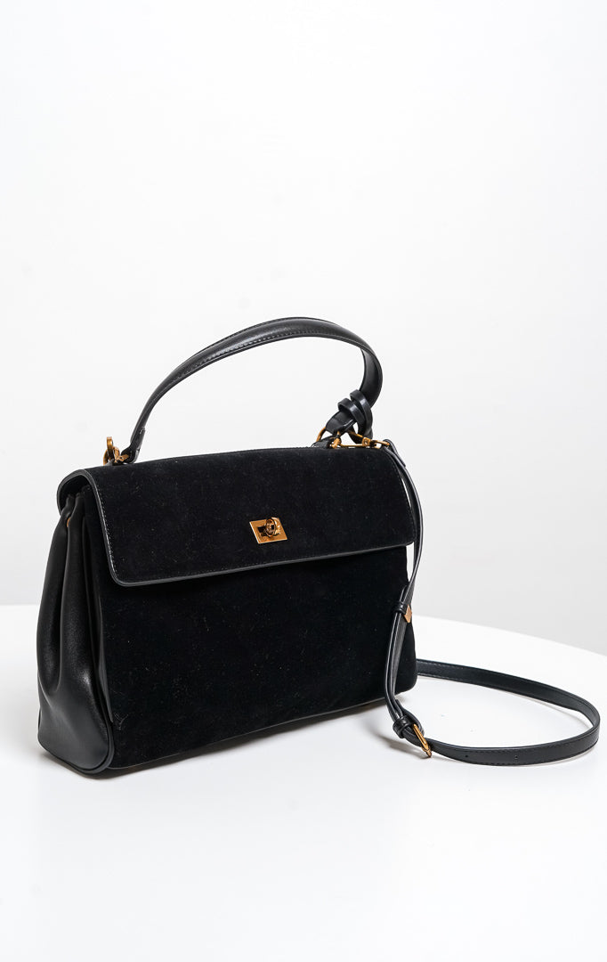Tas wanita Lalitha warna hitam menampilkan kombinasi bahan kulit sintetis dan suede bertekstur lembut, penutup flap dengan kunci putar (twist lock) warna emas, lengkap dengan tali jinjing pendek (handbag) serta tali panjang (sling bag).