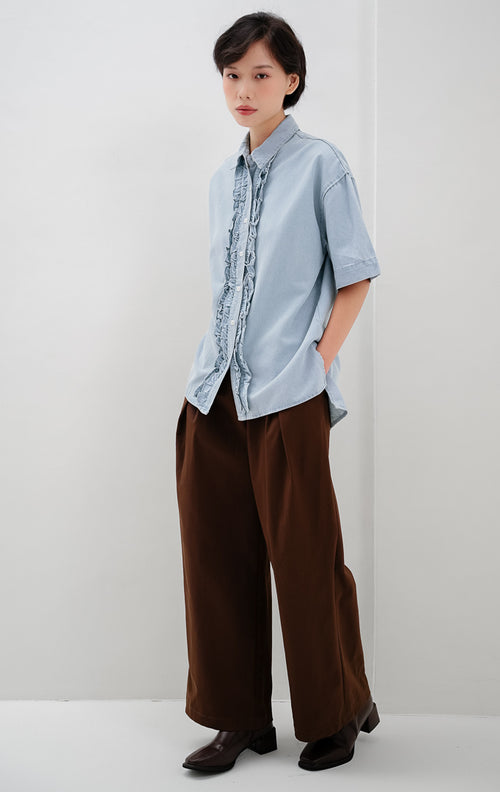 Kemeja denim wanita warna biru muda (light denim) Lavender Top dengan detail kerah klasik, aksen ruffle trim di sepanjang kancing depan, dan siluet relaxed fit.
