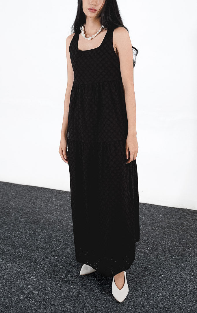 Model wanita mengenakan Layila Dress warna black, gaun mini tanpa lengan dengan detail bordir eyelet bermotif floral di seluruh bagian kain