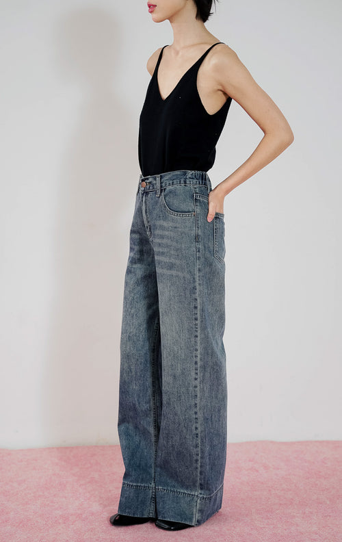Celana jeans wanita Leon Pants dari This Is April warna biru washed denim dengan potongan lurus (straight leg), dipadukan dengan tank top hitam.