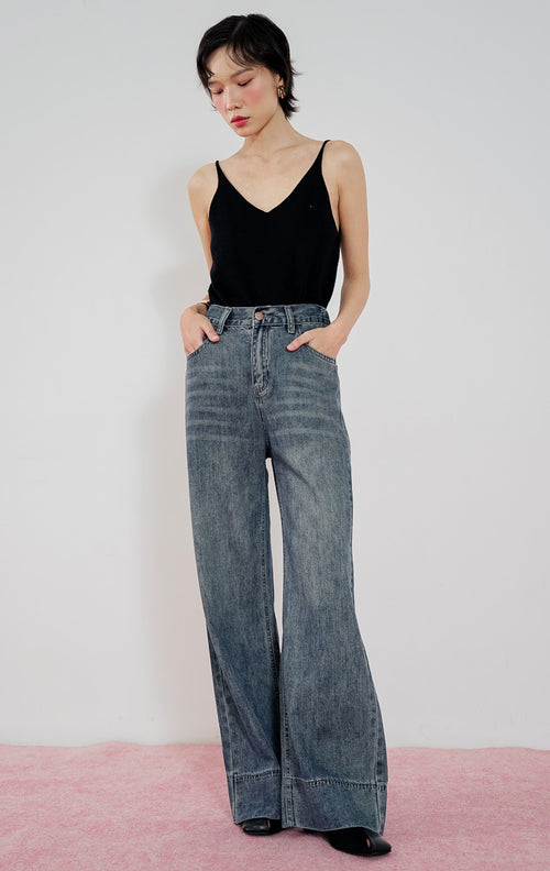 Celana jeans wanita Leon Pants dari This Is April warna biru washed denim dengan potongan lurus (straight leg), dipadukan dengan tank top hitam.