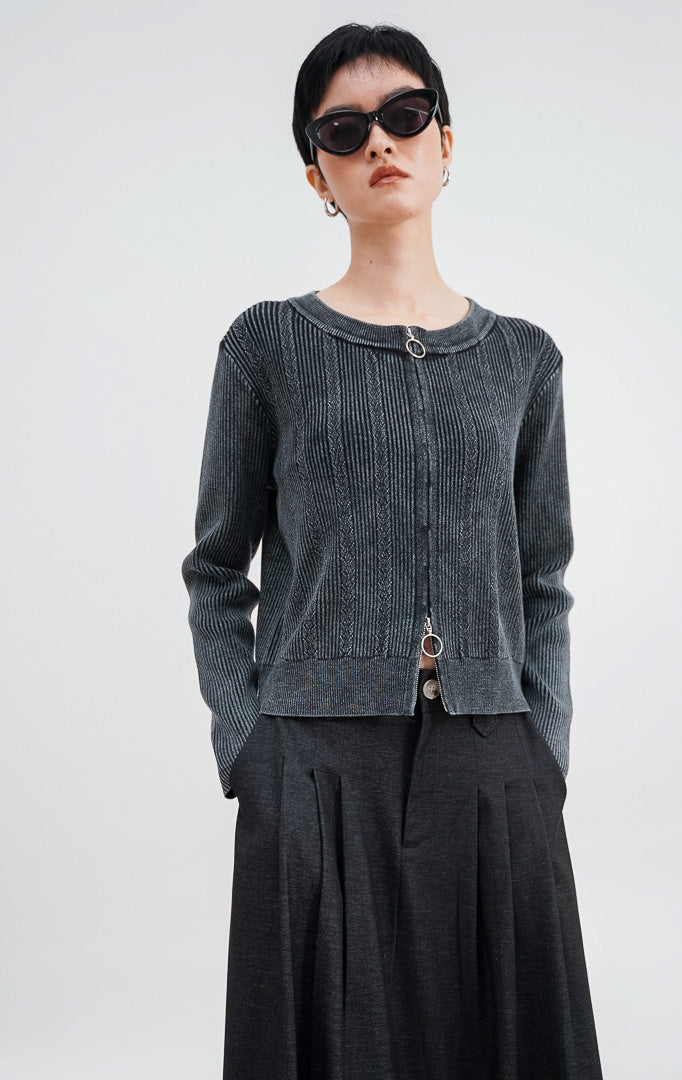 Model mengenakan Leona Cardigan warna grey, kardigan rajut bertekstur kabel dengan dua resleting (double zip) perak di bagian depan dan kerah bulat.