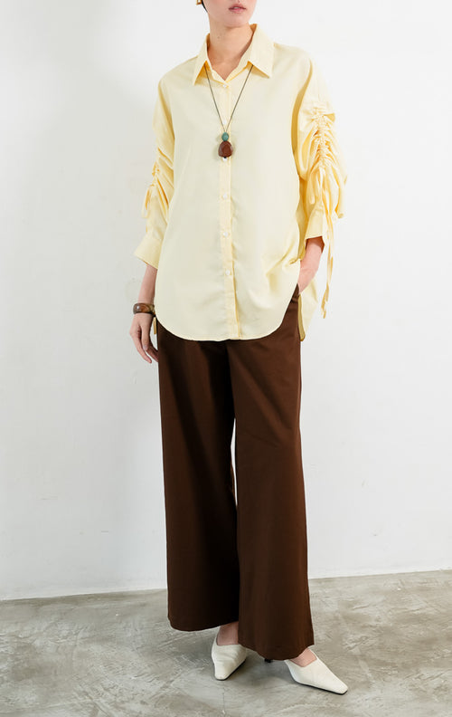 Kemeja wanita lengan panjang warna kuning (yellow) motif garis halus Liliana Top dengan kerah klasik (classic collar), bukaan kancing depan, dan detail tali serut pada bagian lengan (adjustable ruched sleeves with drawstring ties). 


