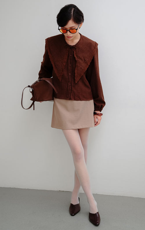 Atasan wanita warna cokelat Linara Top berbahan katun berstruktur dengan detail kerah scalloped Peter Pan untuk tampilan chic dan office look.

