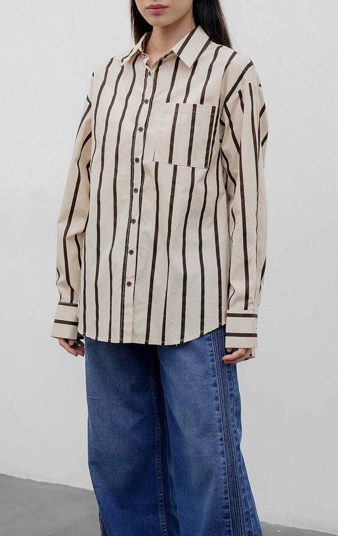 Kemeja wanita oversized lengan panjang warna cokelat (brown) Linette Top bermotif garis vertikal (striped) berbahan campuran katun-poliester dengan saku depan fungsional. 