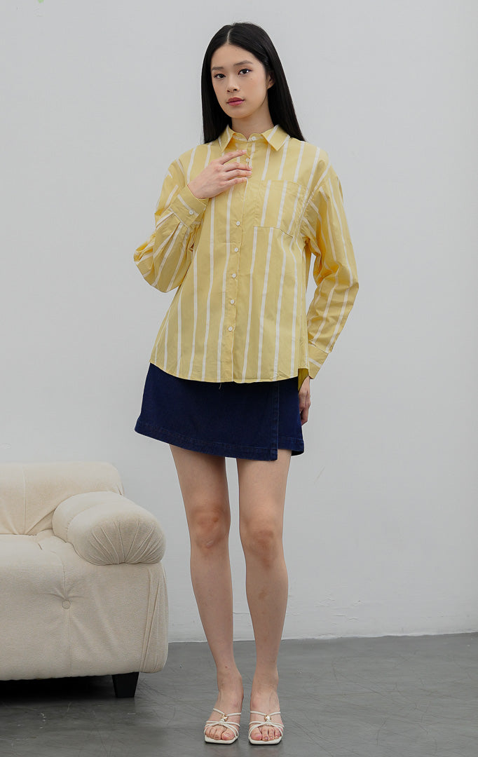 Kemeja wanita oversized lengan panjang warna kuning (yellow) Linette Top bermotif garis vertikal (striped) berbahan campuran katun-poliester dengan saku depan fungsional.