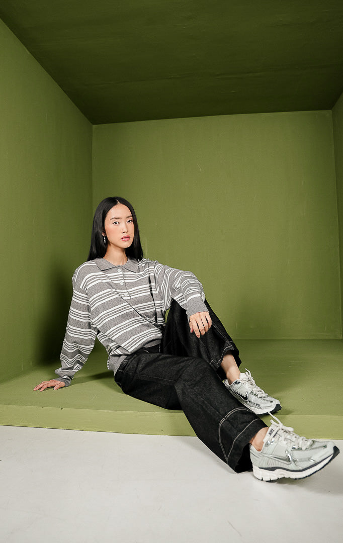 Sweater rajut wanita Lorenda Sweater lengan panjang dengan kerah polo berwarna abu-abu solid, detail tiga kancing depan, dan motif garis horizontal perpaduan warna abu-abu dan putih.