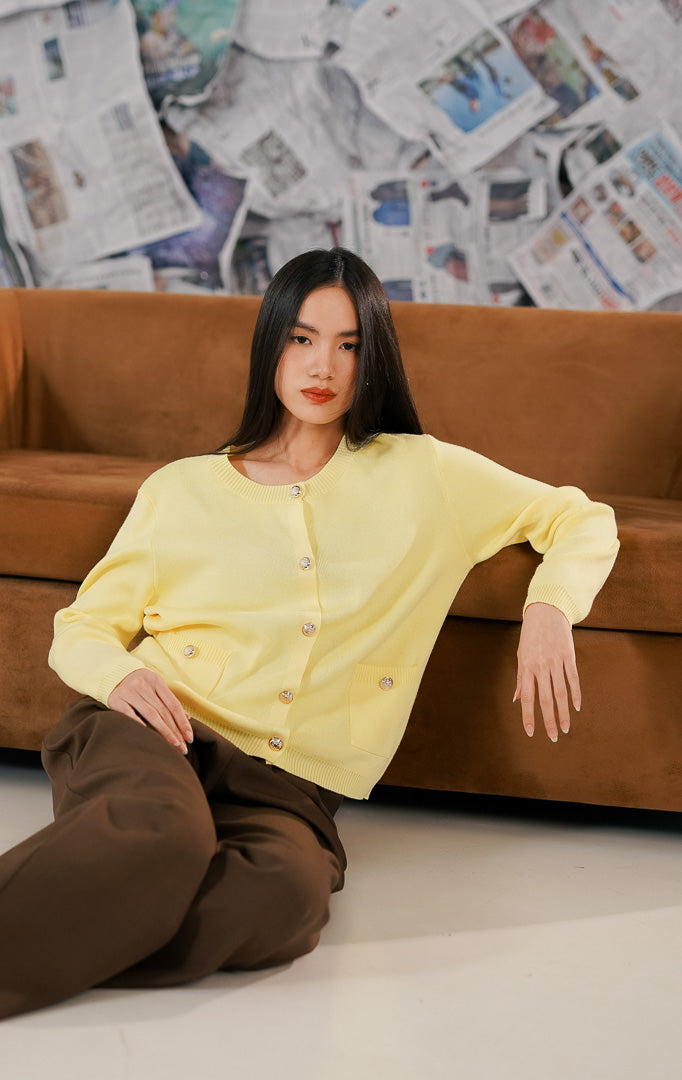 Model mengenakan Lorette Cardigan Yellow, luaran rajut wanita warna kuning cerah dengan dua saku depan fungsional, kancing klasik, dan bahan melar yang nyaman.
