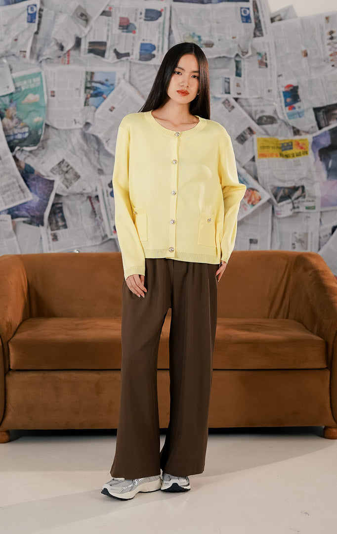 Model mengenakan Lorette Cardigan Yellow, luaran rajut wanita warna kuning cerah dengan dua saku depan fungsional, kancing klasik, dan bahan melar yang nyaman.