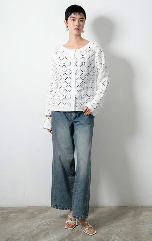 Kardigan rajut wanita lengan panjang warna putih (white) Lucia Cardigan berbahan rajut renda transparan (crochet open-knit) dengan kerah bulat (round neckline) dan bukaan kancing depan warna senada.