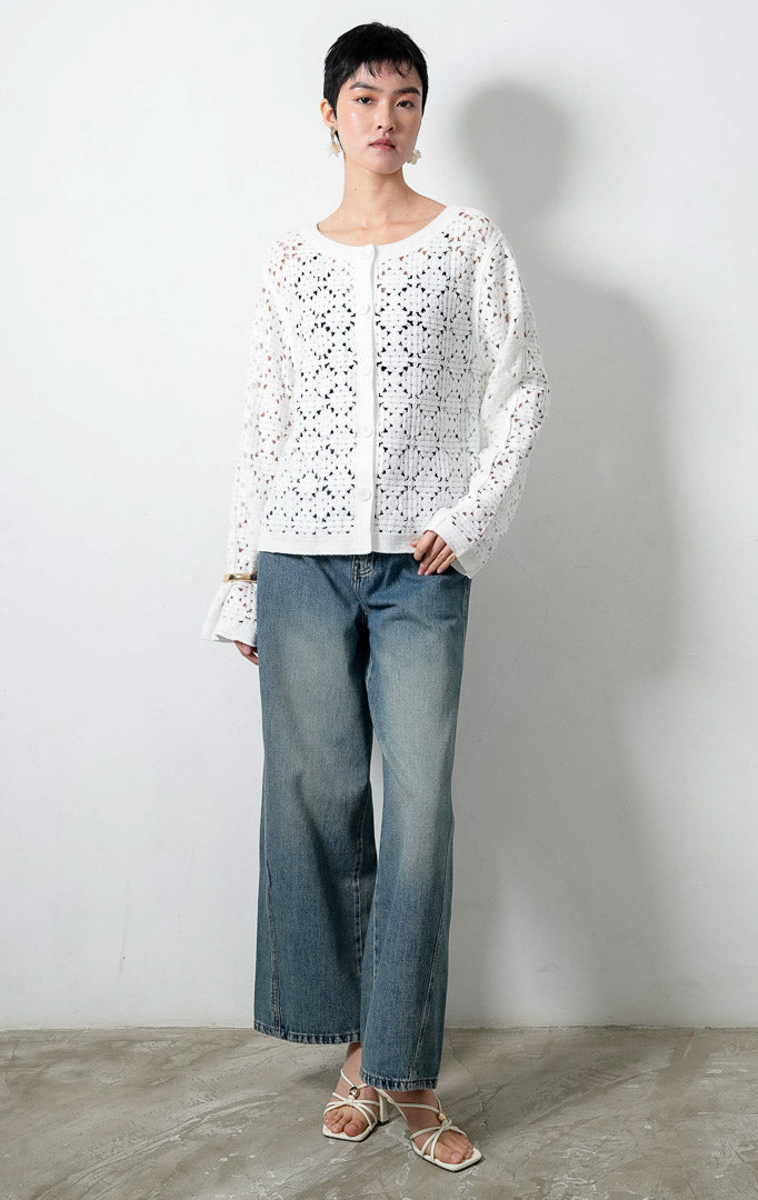 Kardigan rajut wanita lengan panjang warna putih (white) Lucia Cardigan berbahan rajut renda transparan (crochet open-knit) dengan kerah bulat (round neckline) dan bukaan kancing depan warna senada.