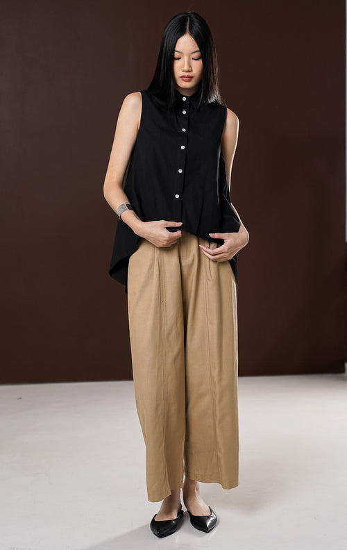 Atasan tanpa lengan wanita Lumira warna hitam , berkerah kemeja dengan deretan kancing depan putih kontras serta potongan hem tumpuk high-low (depan lebih pendek).