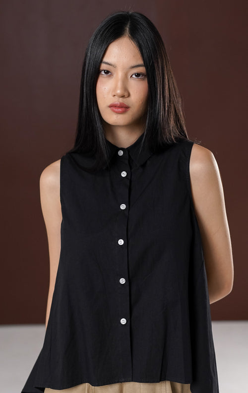 Atasan tanpa lengan wanita Lumira warna hitam , berkerah kemeja dengan deretan kancing depan putih kontras serta potongan hem tumpuk high-low (depan lebih pendek).