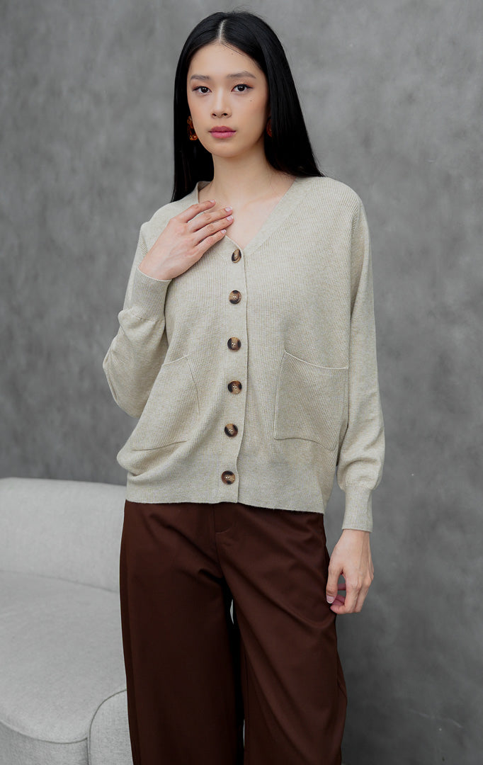 Kardigan rajut wanita model longgar (oversized) warna cokelat muda (khaki) Lumora Cardigan dengan kerah V (V-neck), saku fungsional depan, dan kancing.