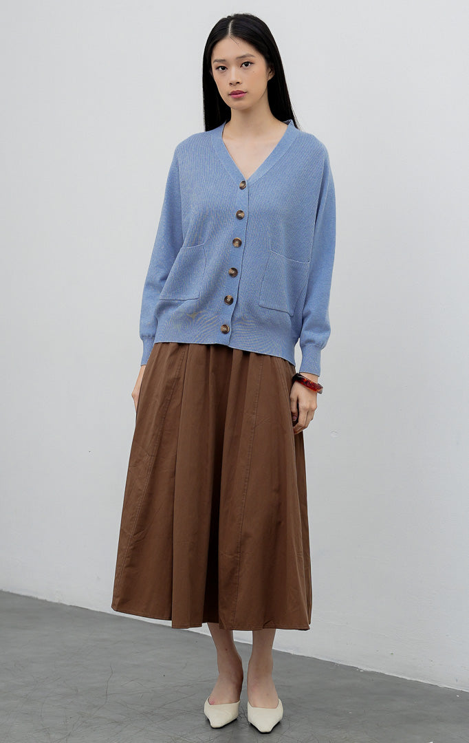 Kardigan rajut wanita model longgar (oversized) warna biru muda (light blue) Lumora Cardigan dengan kerah V (V-neck), dua saku depan fungsional, dan bukaan kancing.