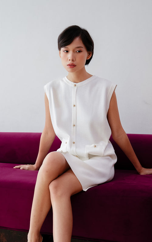 Mini dress wanita tanpa lengan (sleeveless) warna putih Luvenia Dress berbahan stretch knit dengan aksen kancing depan dan kantong fungsional untuk gaya casual dan date night.