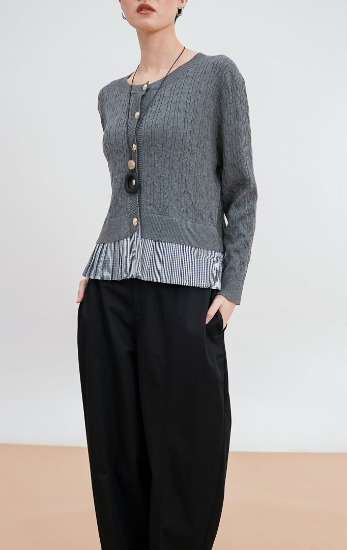 Model mengenakan Malora Cardigan warna grey, kardigan rajut tekstur kepang dengan detail kancing emas dan tambahan hem kain flanel motif kotak hitam putih.