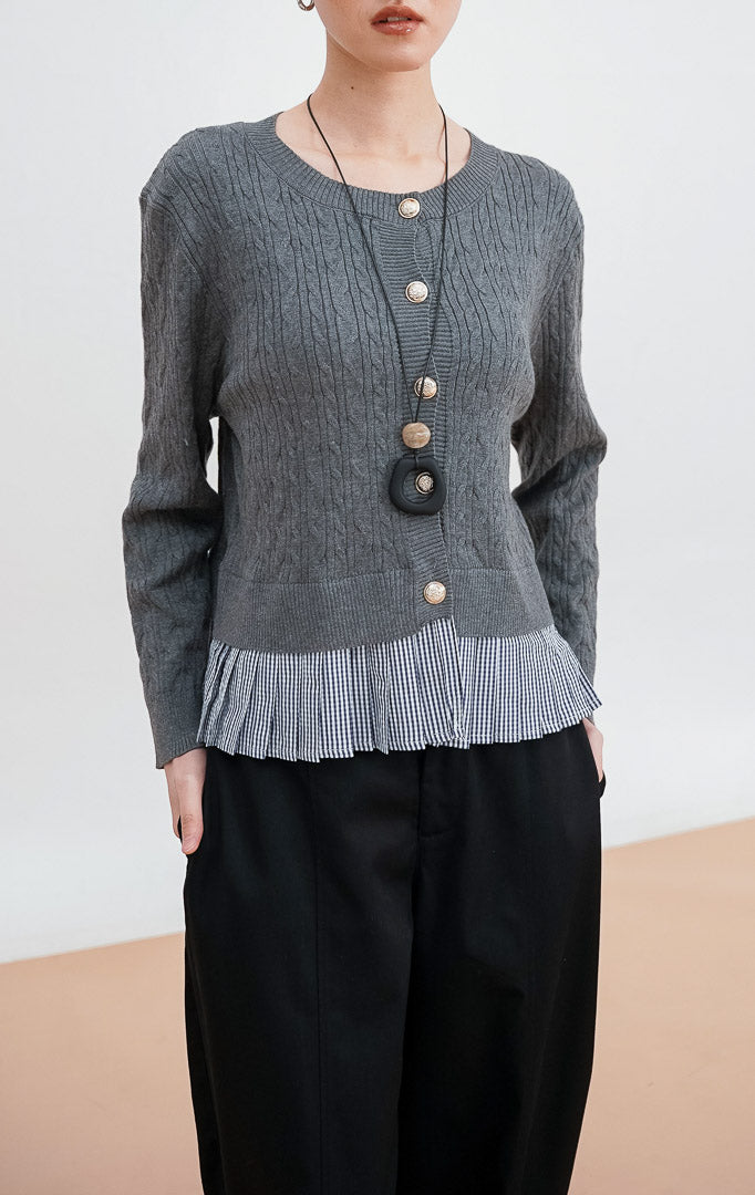 Model mengenakan Malora Cardigan warna grey, kardigan rajut tekstur kepang dengan detail kancing emas dan tambahan hem kain flanel motif kotak hitam putih.