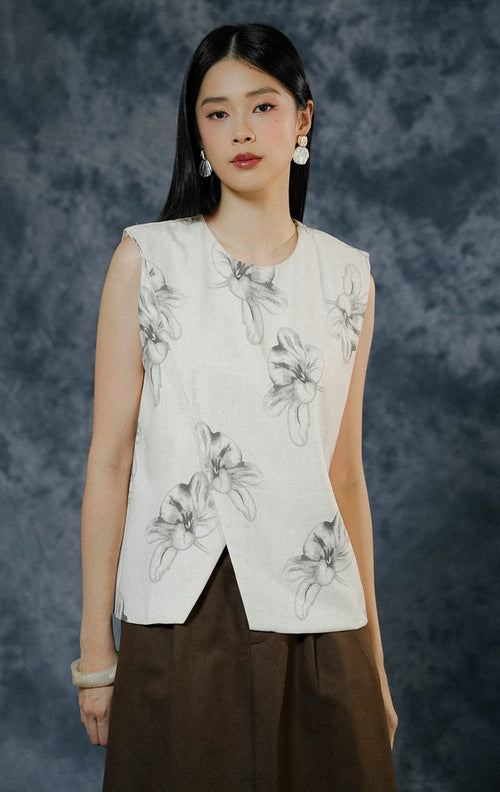 Atasan rompi wanita Marquise warna ivory tanpa lengan dengan motif bunga (floral), menampilkan detail cutting unik di depan, saku aktif, dan kancing hidup. 