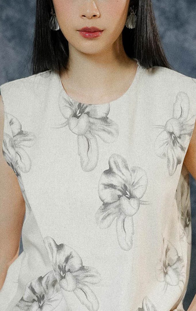 Atasan rompi wanita Marquise warna ivory tanpa lengan dengan motif bunga (floral), menampilkan detail cutting unik di depan, saku aktif, dan kancing hidup. 