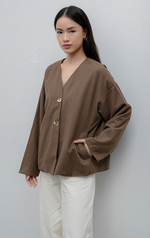 Jaket wanita lengan panjang warna cokelat (brown) Maurissa Jacket berbahan stretch cotton dengan potongan boxy, kerah V-neck, kancing depan, dan saku fungsional.