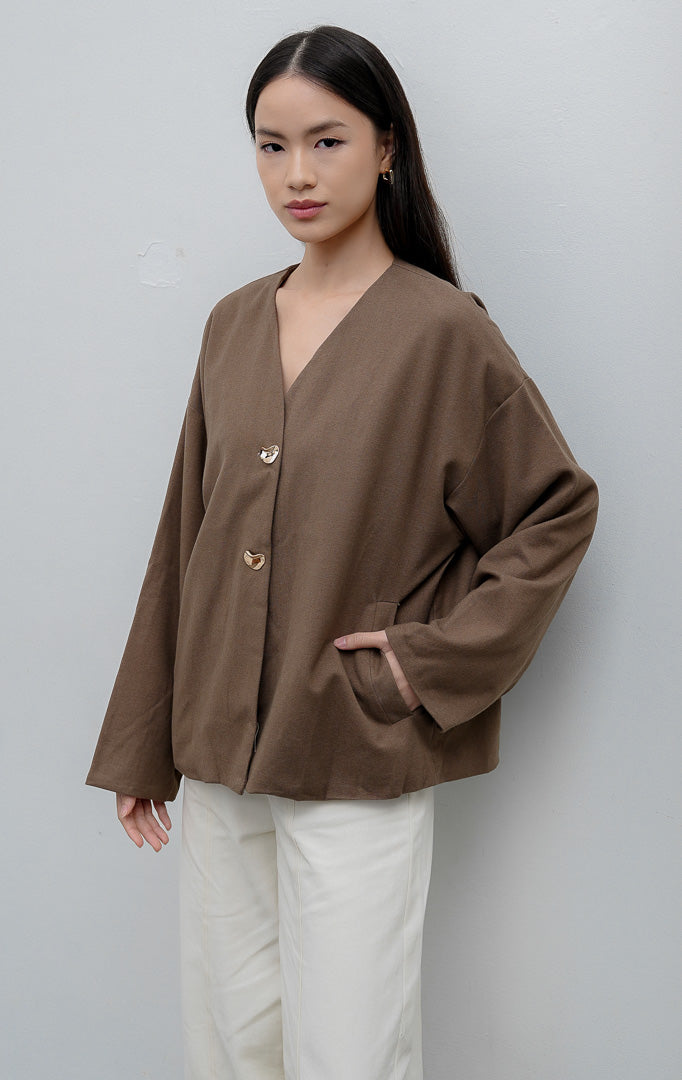 Jaket wanita lengan panjang warna cokelat (brown) Maurissa Jacket berbahan stretch cotton dengan potongan boxy, kerah V-neck, kancing depan, dan saku fungsional.