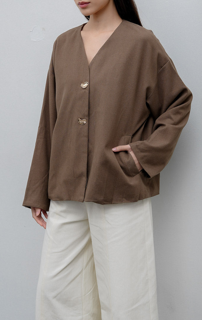 Jaket wanita lengan panjang warna cokelat (brown) Maurissa Jacket berbahan stretch cotton dengan potongan boxy, kerah V-neck, kancing depan, dan saku fungsional.