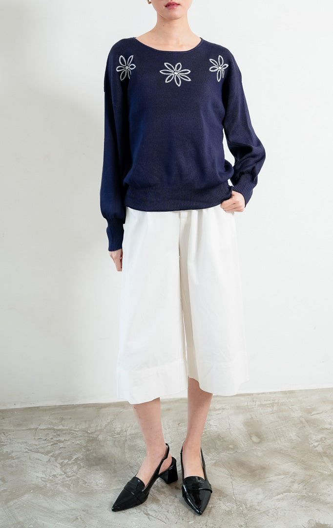Sweter rajut wanita lengan panjang warna biru navy (navy blue) Mayra Sweater berbahan rajut lembut (soft knit) dengan kerah bulat (round neckline) dan aksen bordir bunga putih di bagian dada (white floral embroidery). 
